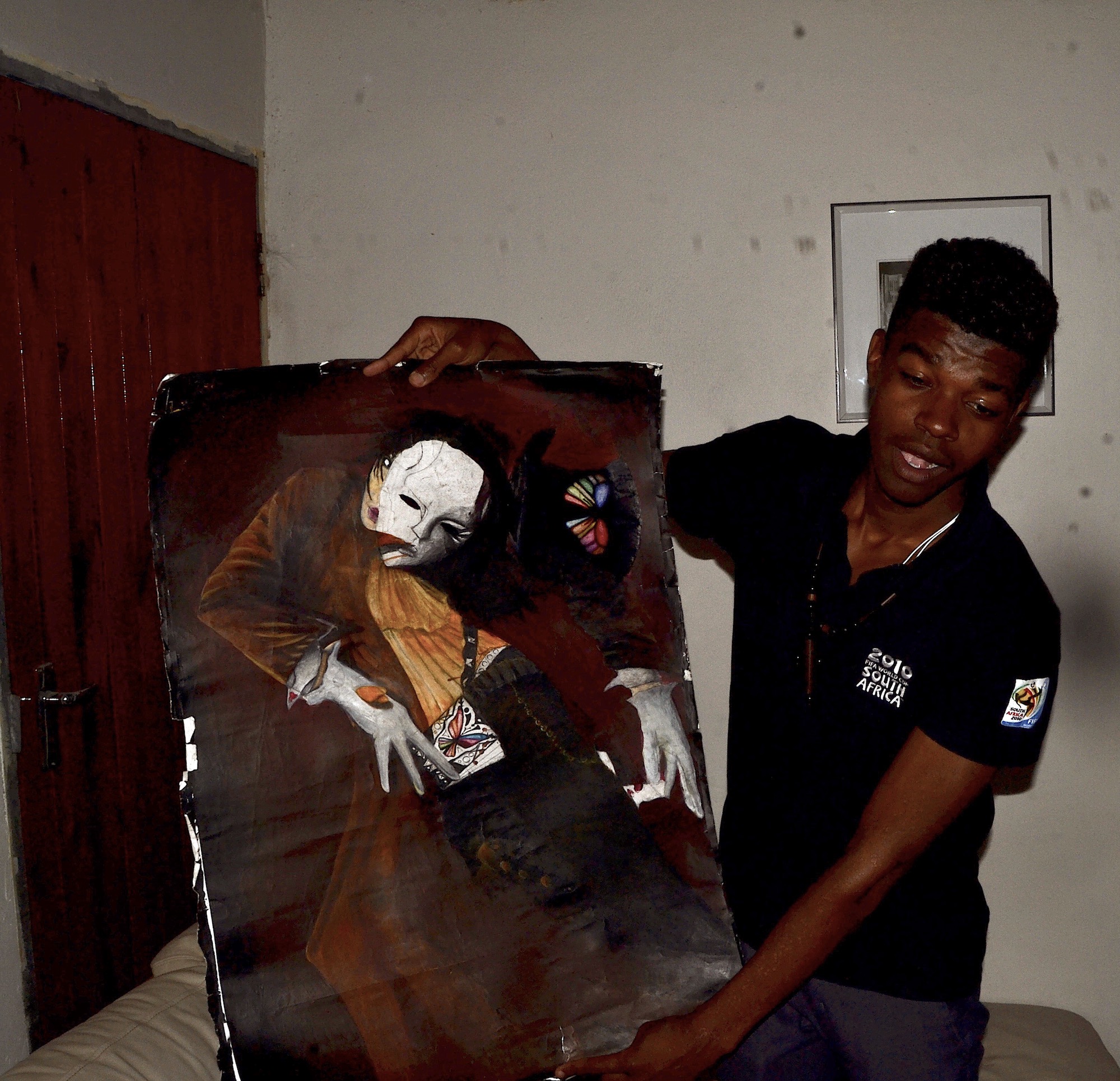 Photo of a young man holding up a painting